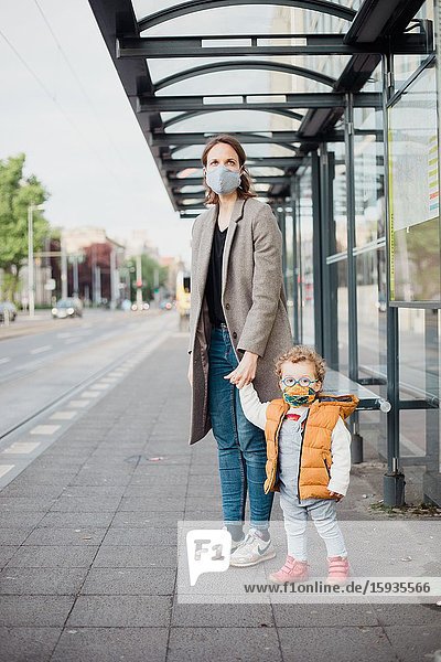 Mother and son with mask waiting for the bus.