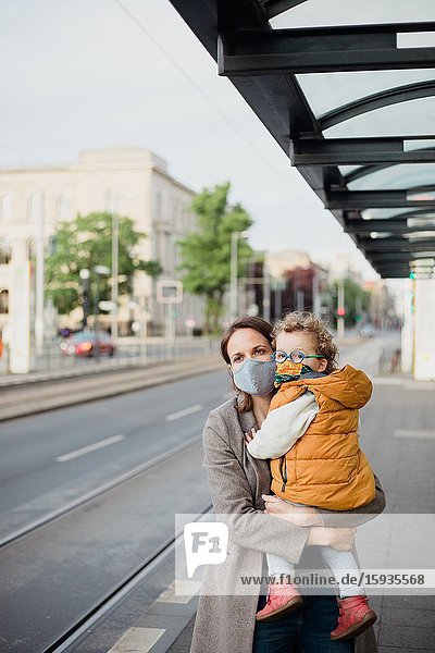 Mother and son with mask waiting for the bus.
