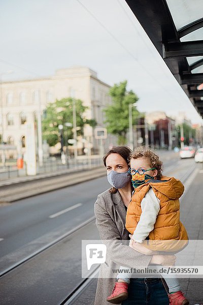 Mother and son with mask waiting for the bus.