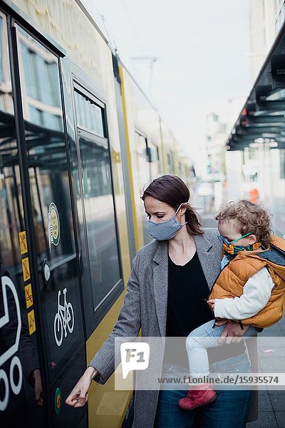 Mother and son taking public transport with mask during corona days.
