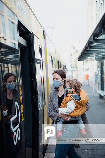 Mother and son taking public transport with mask during corona days.