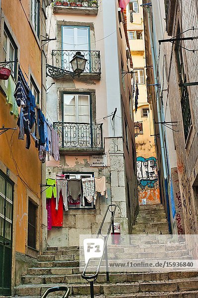Narrow streets with laundry hanging to dry and graffiti in Alfama neighbourhood Lisbon Portugal.