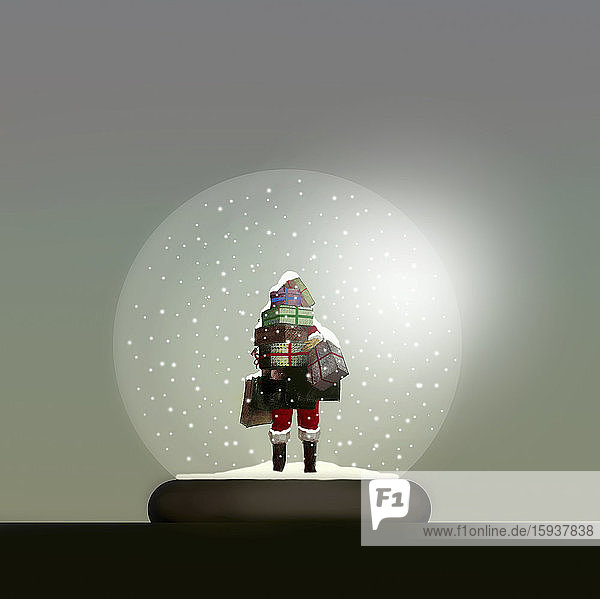 Weihnachtsmann mit einem Stapel Geschenke in einer Schneekugel