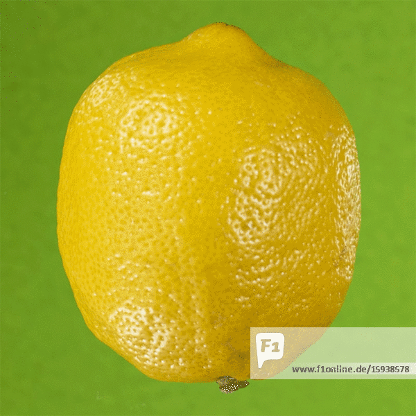 Sich auflösende Zitrone vor grünem Hintergrund,  Stop-Motion-Effekt