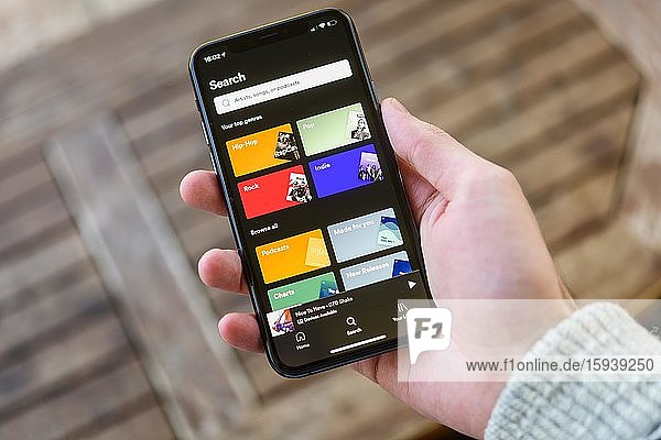Hand holds iPhone 11 with Spotify App on display  music streaming  iOS  Smartphone  Germany  Europe