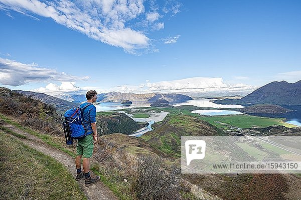 Wanderer hält Ausschau auf dem Wanderweg zu Rocky Peak  Blick auf Wanaka See und Berge  Glendhu Bay  Otago  Südinsel  Neuseeland  Ozeanien
