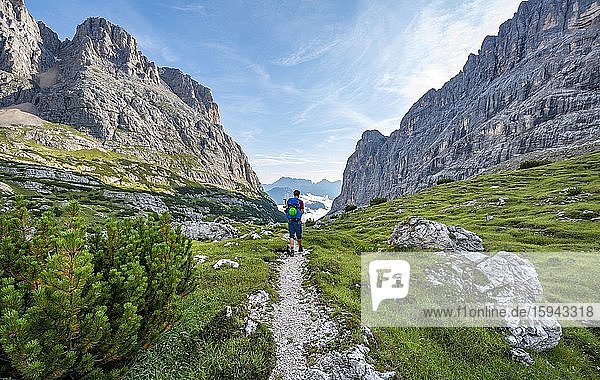 Hiker  mountaineer on a path between rocky mountains  Sorapiss circuit  behind mountain Punte Tre Sorelle  Dolomites  Belluno  Italy  Europe