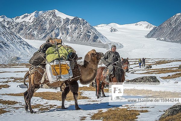 Mongolian shepherd on horseback with a clumsy animal with luggage takes two tourists to the Mongolian Altai Mountains  Bayan-Ulgii Province  Mongolia  Asia