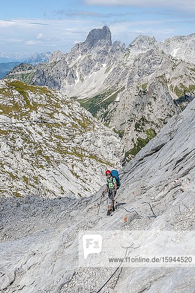 Wanderin auf felsiger mit Drahtseil gesicherter Route von Simonyhütte zur Adamekhütte  felsiges alpines Gelände  Ausblick auf Bergpanorama und Vorderer Gosausee  Salzkammergut  Oberösterreich  Österreich  Europa