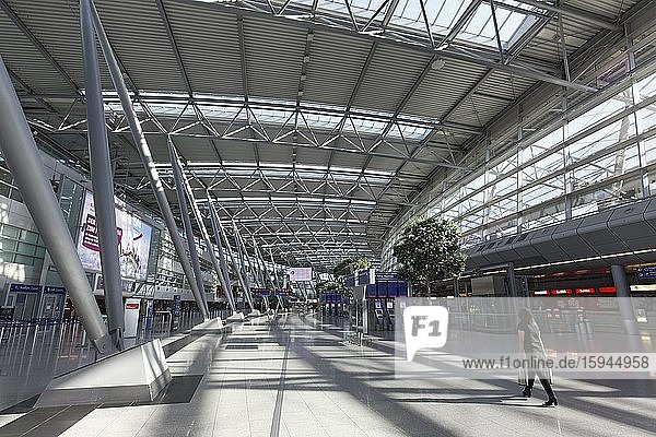 Einzelne Person geht durch die leere Abflughalle  Flughafen Düsseldorf während der Corona-Pandemie  Nordrhein-Westfalen  Deutschland  Europa