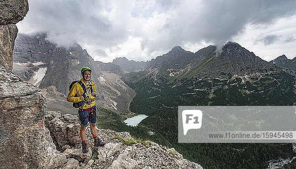 Young man  hiker with view of Lago di Sorapis and the peaks of Cime di Laudo and La Cesta  Via Ferrata Vandelli via ferrata  Sorapis circuit  Dolomites  Belluno  Italy  Europe
