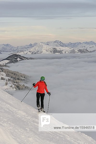 Skifahrerin steht an Skipiste  hinten Bergpanorama über Wolkendecke  SkiWelt Wilder Kaiser  Brixen im Thale  Tirol  Österreich  Europa