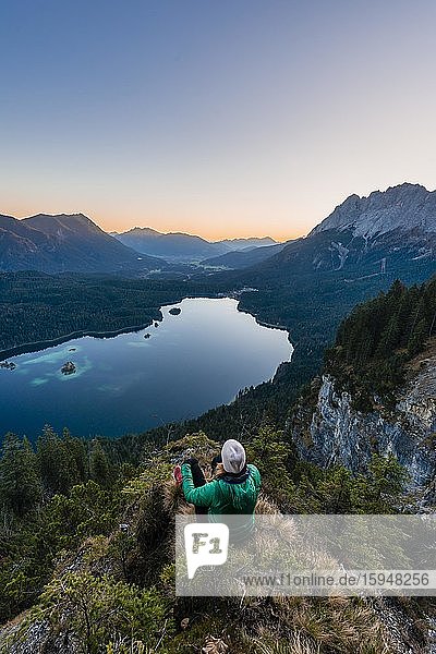Frau blickt über Eibsee und Zugspitzmassiv mit Zugspitze  Sonnenaufgang  Wettersteingebirge  bei Grainau  Oberbayern  Bayern  Deutschland  Europa