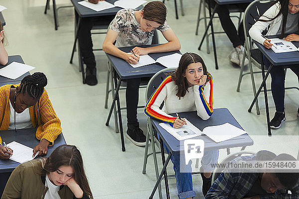 Thoughtful high school girl taking exam at desk in classroom