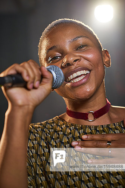 Porträt einer glücklichen jungen Musikerin  die ins Mikrofon singt