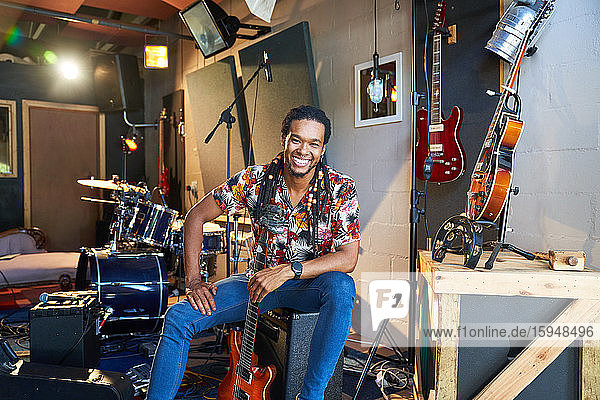 Portrait happy confident male musician with guitar in recording studio