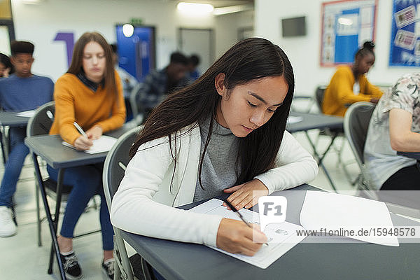 Fokussierte High-School-Schülerin nimmt Prüfung am Schreibtisch im Klassenzimmer ab