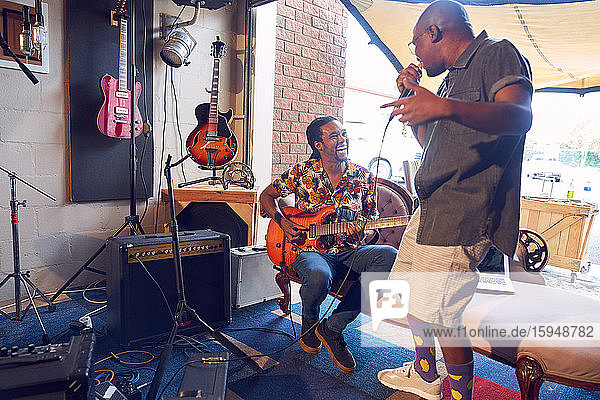 Happy male musicians practicing in garage recording studio