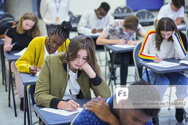 High-School-Schülerin legt Prüfung am Schreibtisch im Klassenzimmer ab