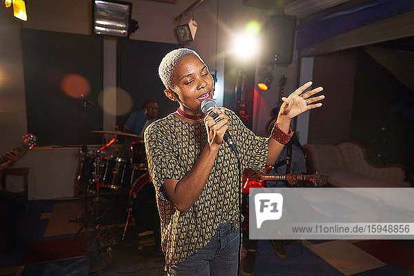 Junge Musikerin singt im Aufnahmestudio ins Mikrofon