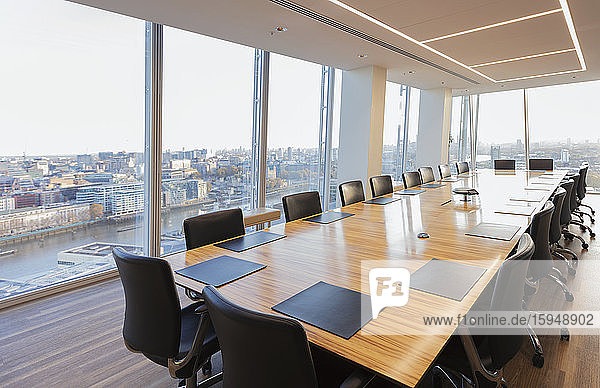 Langer Konferenztisch in modernem Hochhausbüro mit Blick auf die Stadt