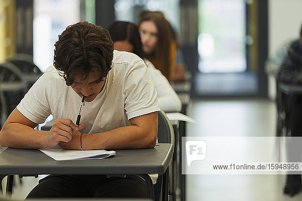 Fokussierter High-School-Schüler nimmt Prüfung am Schreibtisch im Klassenzimmer ab