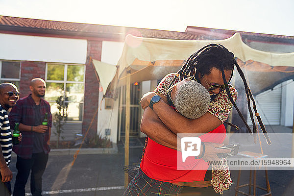 Glückliche Freunde umarmen sich auf sonnigem Parkplatz