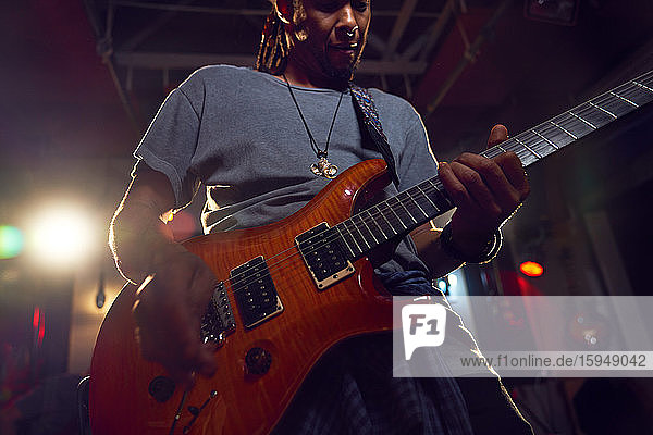 Männlicher Musiker spielt E-Gitarre auf der Bühne