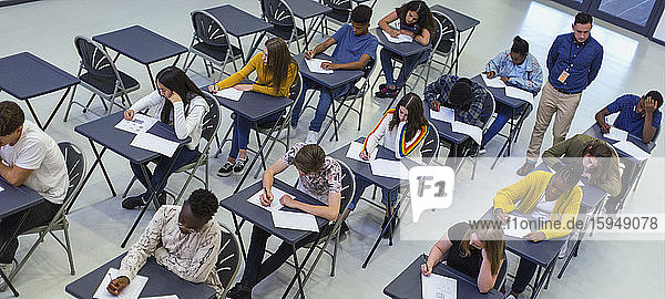 Ausbilder  der Gymnasiasten beaufsichtigt  die am Schreibtisch Prüfungen ablegen