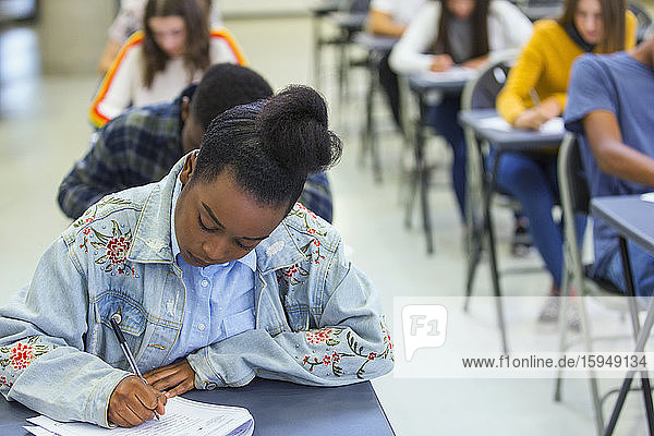 Fokussierte High-School-Schülerin nimmt Prüfung am Schreibtisch im Klassenzimmer ab