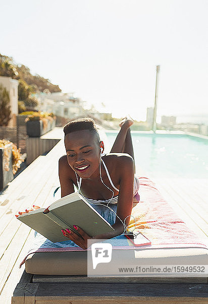 Frau beim Sonnenbaden  Lesen eines Buches auf einem sonnigen Liegestuhl am Pool