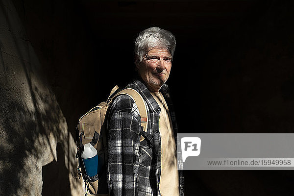 Porträt eines älteren Mannes mit Rucksack bei Sonnenlicht