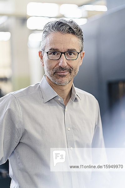 Portrait of a mature businessman standing in company  wearing glasses