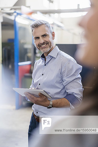 Smiling businessman with tablet and businesswoman having a work meeting in a factory