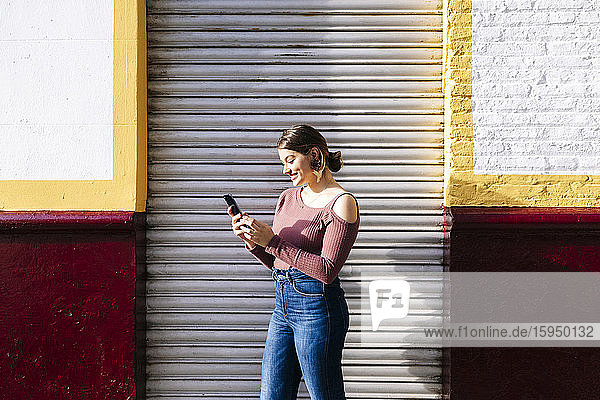 Glückliche Frau benutzt Smartphone in einem Gebäude in der Stadt
