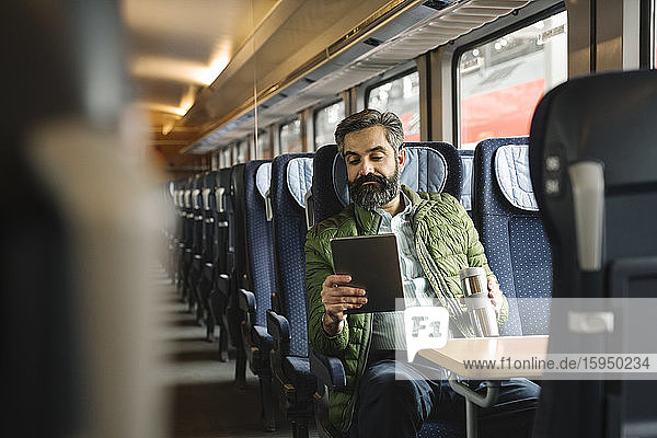 Man sitting in train using tablet