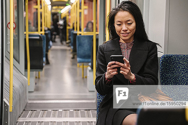 Junge Frau benutzt Smartphone in einer U-Bahn