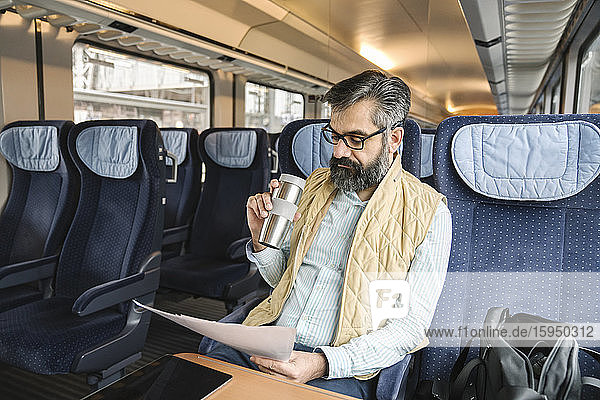 Mann sitzt im Zug und liest Dokumente