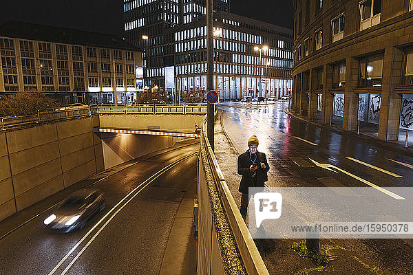 Mann benutzt nachts in der Stadt ein Smartphone