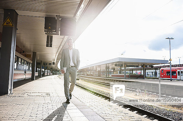 Young businessman walking on station platform in backlight