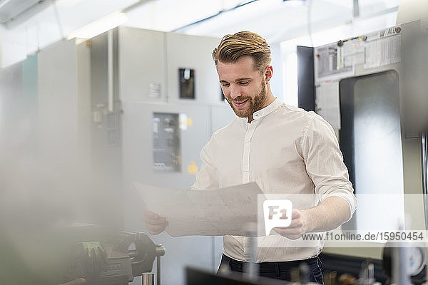 Young man looking at plan in a factory