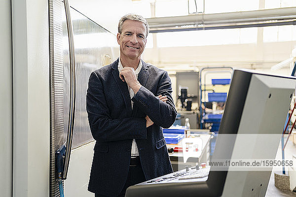 Mature businessman standing in production floor of factory