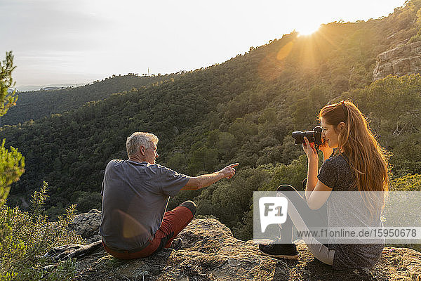 Junge Frau fotografiert ihren Vater bei Sonnenuntergang in den Bergen