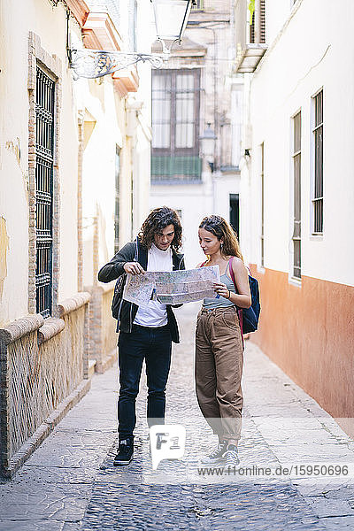 Ein Paar liest die Karte in voller Länge  während es in einer engen Straße in Santa Cruz  Sevilla  Spanien  steht
