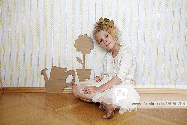 Portrait of girl playing with cardboard watering can and flower