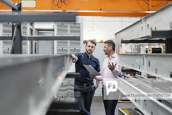 Two men discussing a plan in a factory