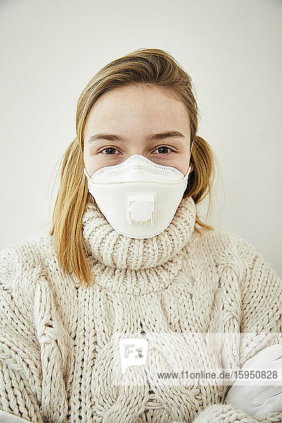 Porträt einer blonden Frau  die zu Hause eine FFP2-Maske trägt