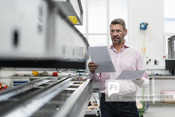 Mature man holding papers in a factory