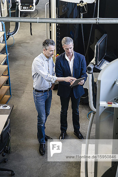 Businessmen in factory  having a meeting  using digital tablet