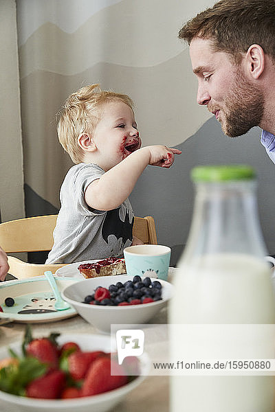 Kleiner Junge mit Vater amüsiert sich am Frühstückstisch